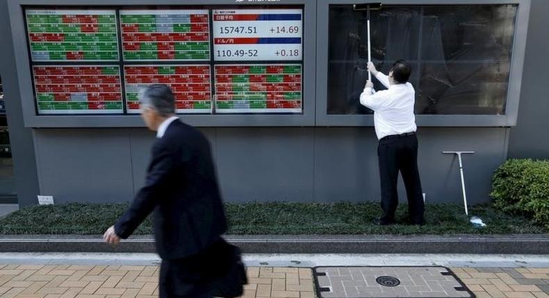 A man (R) cleans electronic boards showing Japan's Nikkei average, the exchange rate between the Japanese yen against the U.S. dollar and stock quotation outside a brokerage in Tokyo, Japan, in this April 6, 2016 file photo. REUTERS/Issei Kato/Files