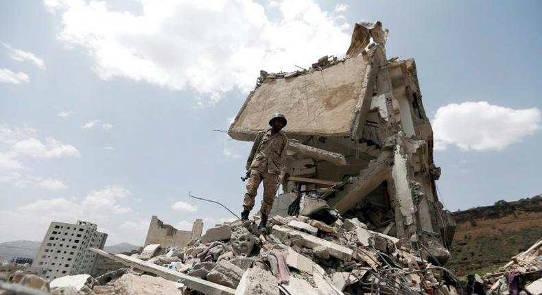 A Yemeni soldier stands on the debris of a house hit in an air strike on a residential district in the capital Sanaa, on August 26, 2017