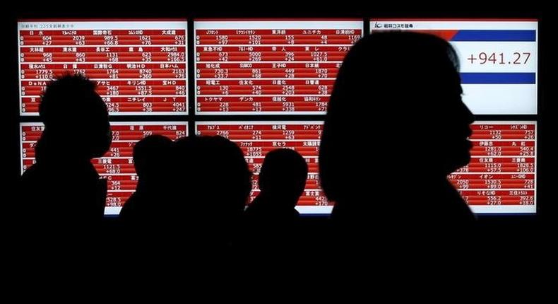 Pedestrians walk past an electronic stock quotation board outside a brokerage in Tokyo, Japan January 22, 2016. REUTERS/Toru Hanai