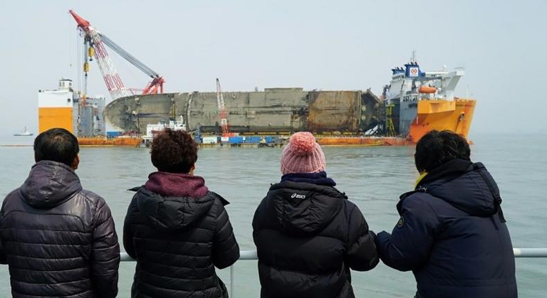 Relatives of the missing from the Sewol ferry disaster look at the damaged ferry during a memorial service from a ship off the coast of the southern South Korean island of Jindo on March 28, 2017