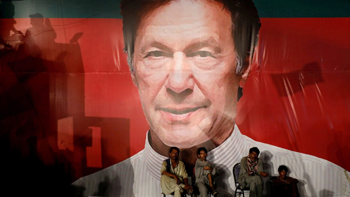 FILE PHOTO: Labourers, who set up the venue, sit under a wall with a billboard displaying a photo of