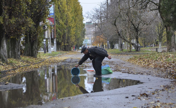 Miejscowy mężczyzna zbiera wodę z kałuży w mieście Chersoń
