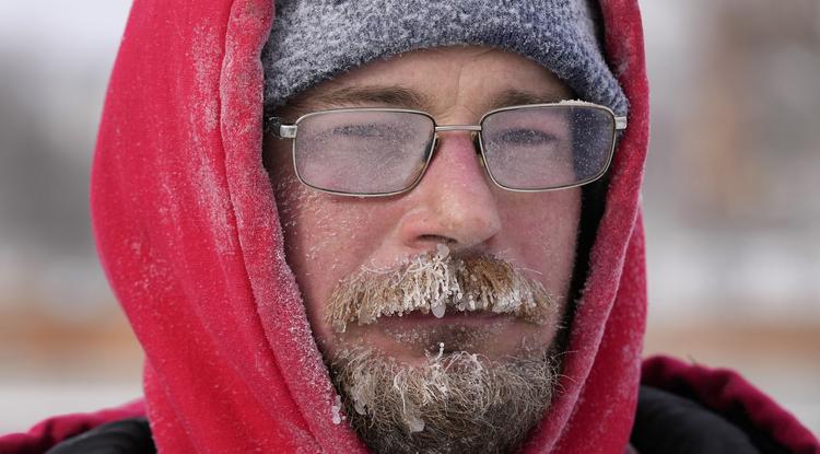Jég és hó van Mark Sorter arcára fagyva, miközben havat takarít le egy városi jégpályáról az Iowa állambeli Des Moines-ban 2022. december 23-án. 