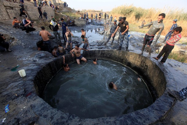 People with Iraqi security forces swim in a sulphur pond in Hammam al-Ali, south of Mosul