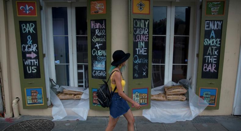 A woman walks past a cigar lounge and bar protected by sand bags in the French Quarter of New Orleans, in preparation for tropical storm Barry