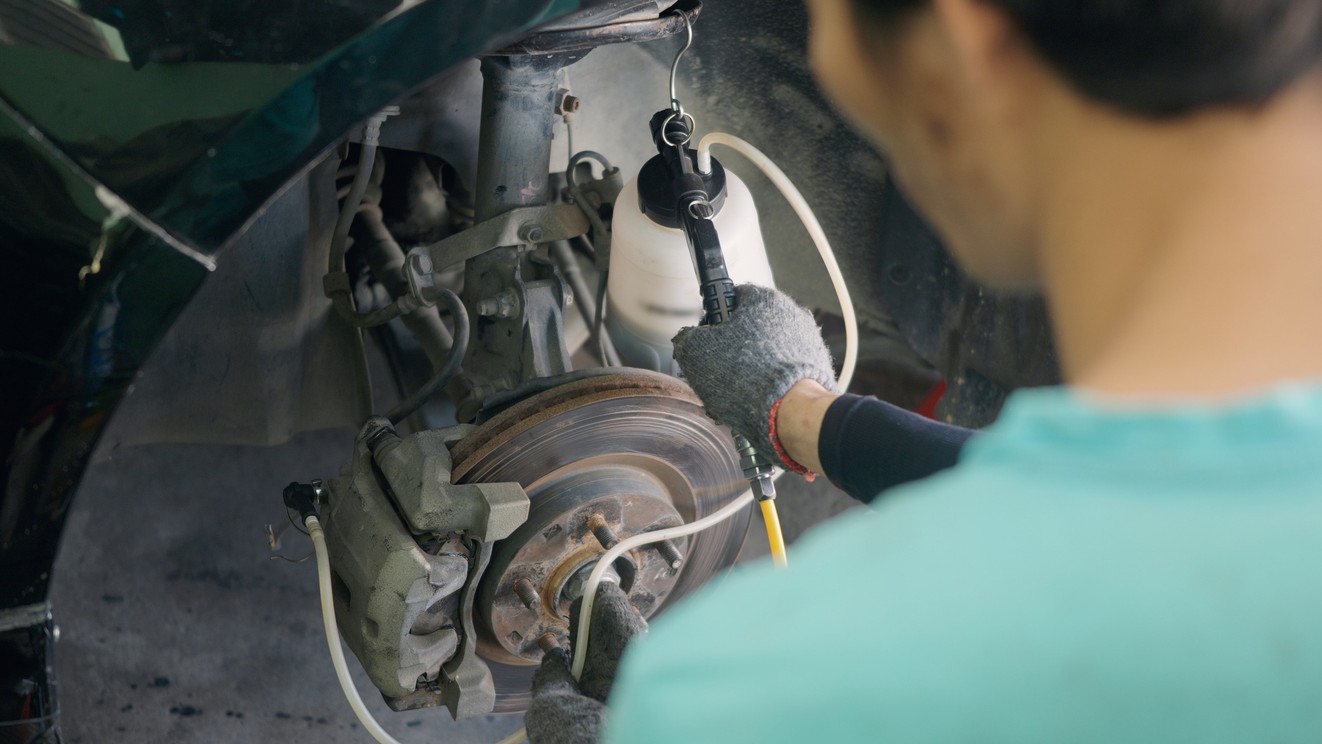 Mechanik vymieňa brzdovú kvapalinu v servise.