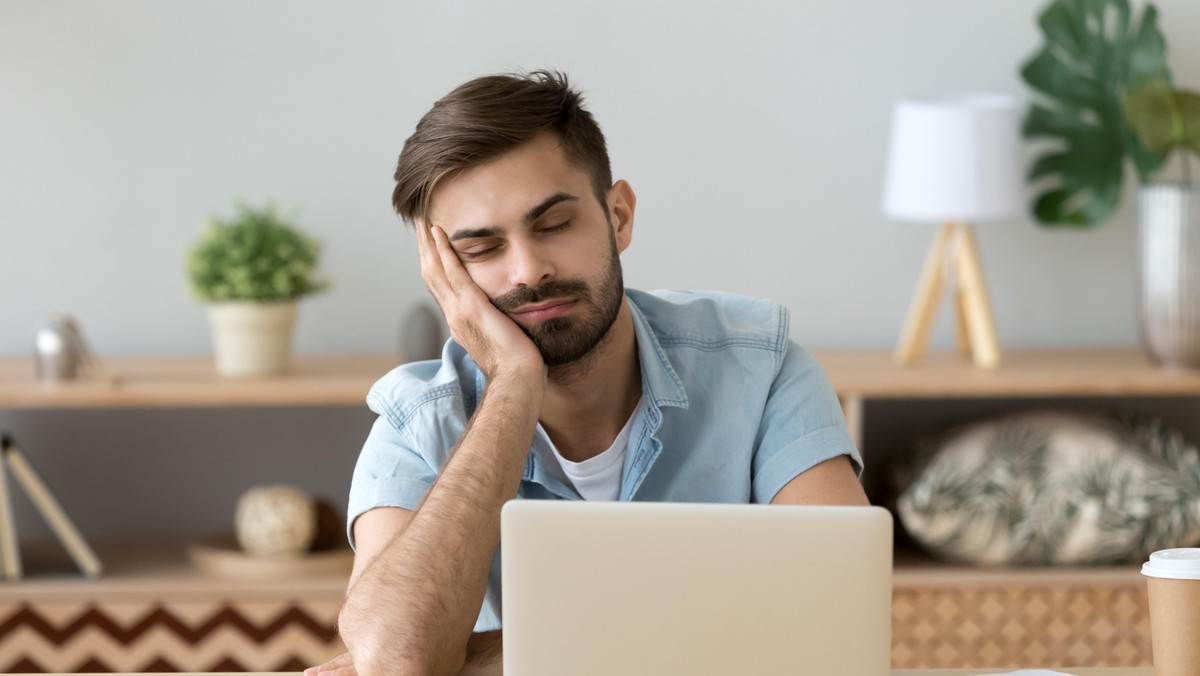 Exhausted man fall asleep near laptop at home workplace