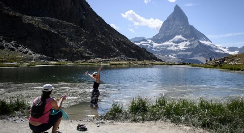 A tourist poses for a picture in the Riffelsee mountain lake with the Matterhorn mountain in background above the resort of Zermatt as heatwave sweeps across Europe