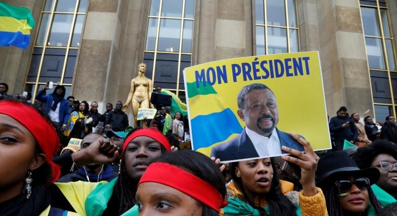 Supporters of Gabonese opposition leader Jean Ping wrapped in Gabonese flags gesture after his speech on October 29, 2016 on the Human Rights Esplanade in Paris