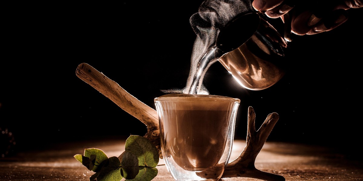 Male hand pouring water from pitcher into the coffee cup