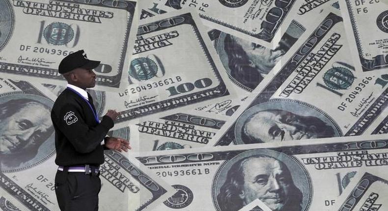 A security guard walks past a montage of U.S. dollar bills outside a currency exchange bureau in Kenya's capital Nairobi, July 23, 2015.    REUTERS/Thomas Mukoya/File Photo