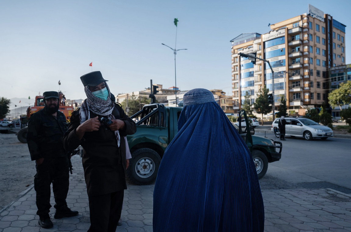 Policjanci przesłuchują kobietę żebrzącą na ulicy w Kabulu, sierpień 2022 r.