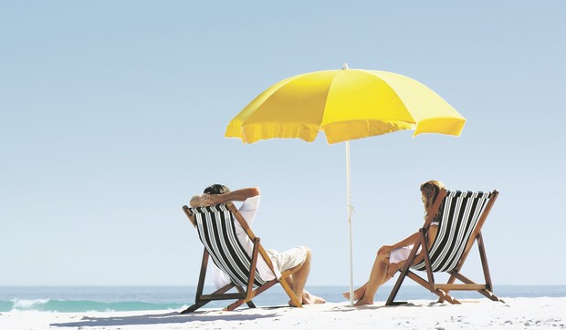 stock-photo-beach-summer-couple-on-island-vacation-holiday-relax-in-the-sun-on-their-deck-chairs-under-a-yellow-97745612