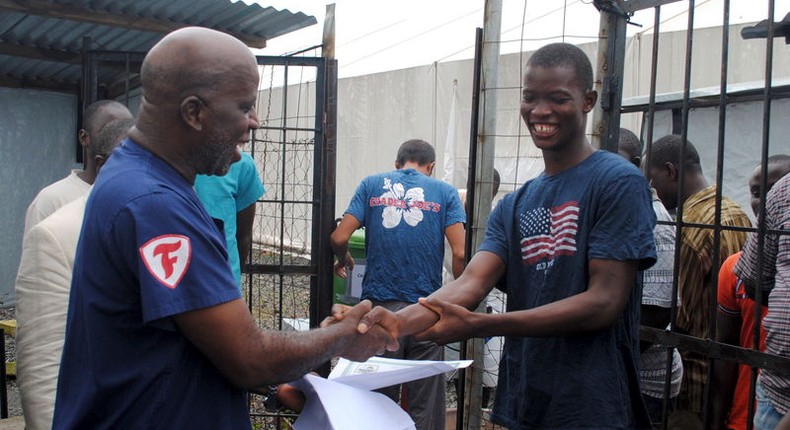 Cassius Kollie (R), 24, one of four people discharged on Monday from an Ebola treatment unit, receives a certificate for being cured of the disease in Paynesville, Liberia, July 20, 2015. REUTERS/James Giahyue