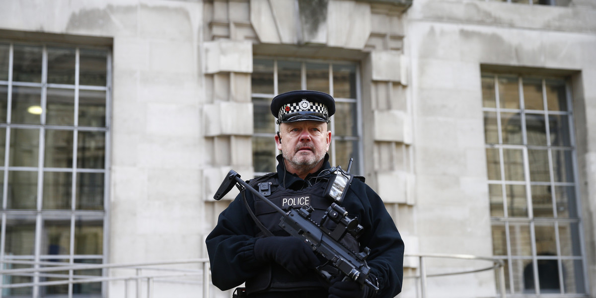 An armed police officer stands on duty outside a government building in Westminster, central London.