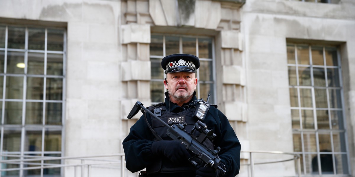 An armed police officer stands on duty outside a government building in Westminster, central London.