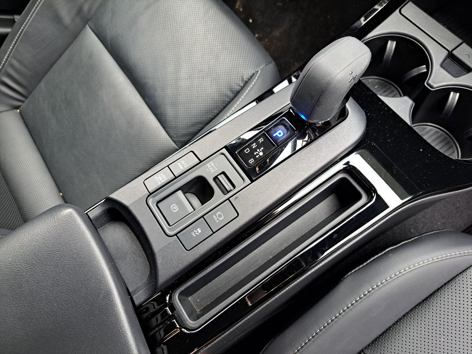 Toyota Prius - na środkowej konsoli są miejsca na drobiazgi, podstawki na kubki oraz spory schowek. Przy wybieraku skrzyni biegów mamy przyciski, m.in. włączające tryb elektryczny.