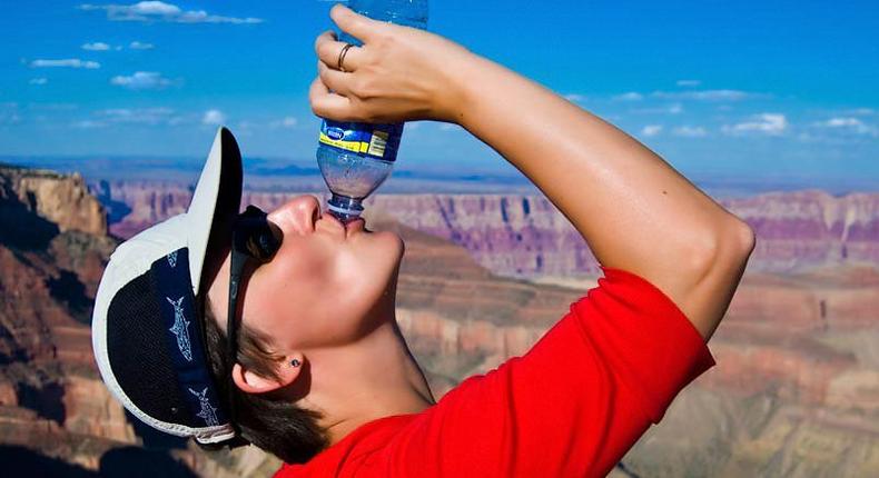 hiker drinking bottled water in desert