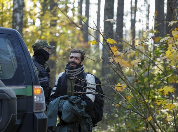 Strażnik graniczny z uchodźcą w lesie koło Szymek na granicy z Białorusią
