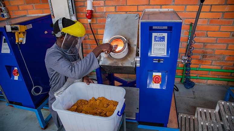 A worker at Aldango Gold Refinery puts gold powder into a high temperature heating device to melt.