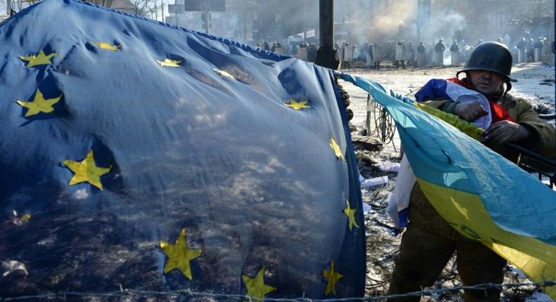 An anti-government opposition activist places European Union and Ukrainian flags side by side at a barricade in Kiev on February 2, 2014