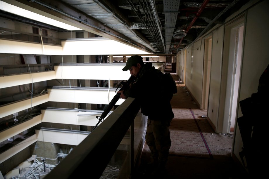 An Iraqi soldier holds his weapon while looking over a balcony in the Ninewah Oberoi Hotel in Mosul.