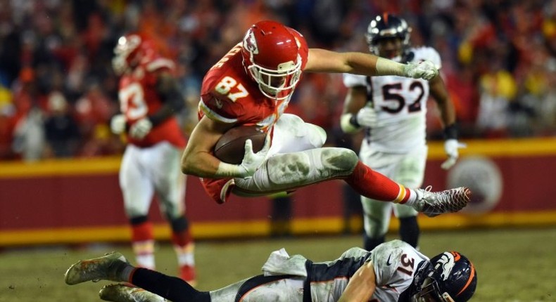 Tight end Travis Kelce of the Kansas City Chiefs leaps over free safety Justin Simmons of the Denver Broncos during their game at Arrowhead Stadium in Kansas City, Missouri, on December 25, 2016