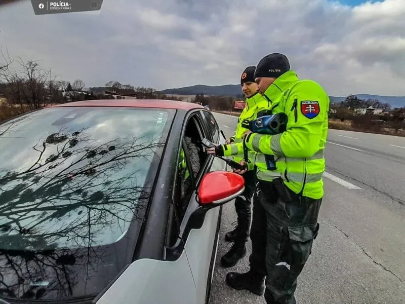 Vodič pokojne komunikuje s policajtom cez stiahnuté okienko svojho vozidla.