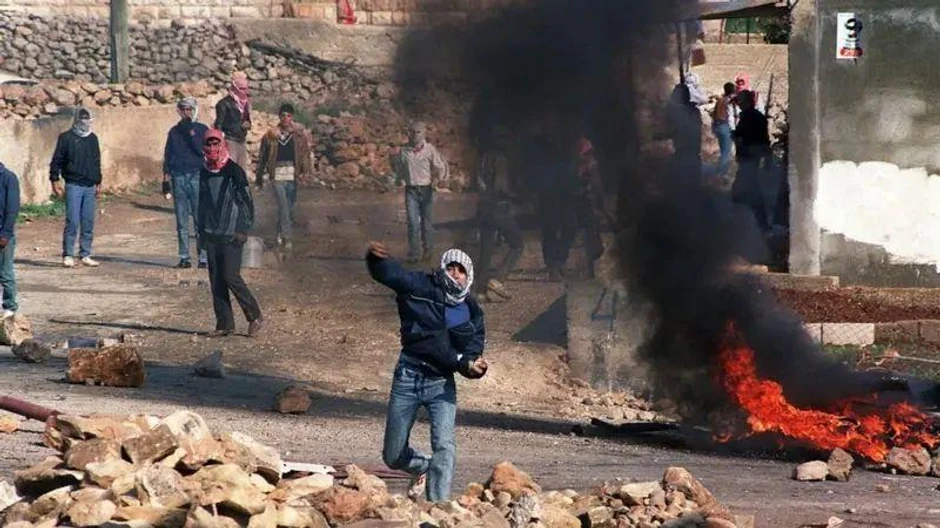 Palestinski demonstranti bacaju kamenje na izraelsku policiju za razbijanje demonstracija u selu Hizme u Severnom Jerusalimu, 21. decembra 1987, proglašenim „Danom mira" u znak podrške Palestincima na Okupiranim teritorijama | Foto: Getty Images
