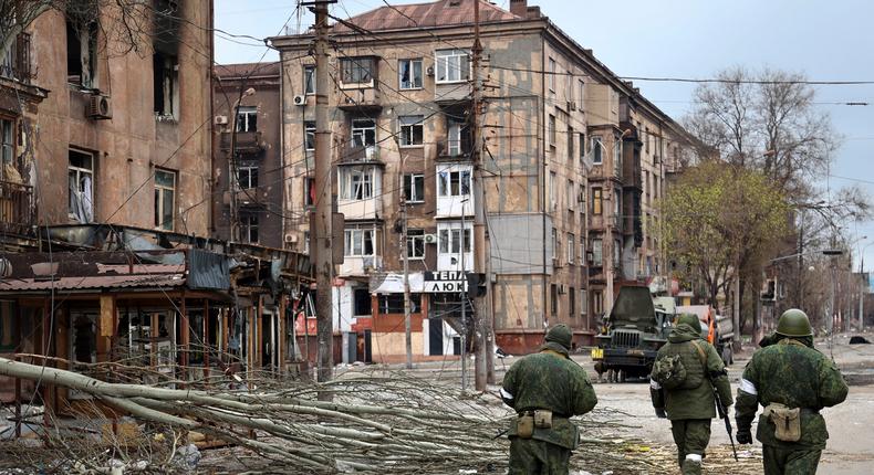 Servicemen of Donetsk People's Republic militia walk past damaged apartment buildings in an area controlled by Russian-backed separatist forces in Mariupol, Ukraine on Saturday, April 16.