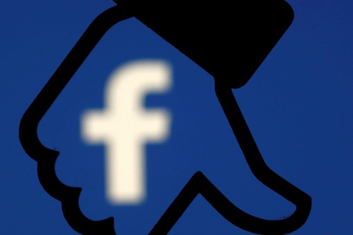 A 3D-printed Facebook dislike button is seen in front the Facebook logo, in this illustration