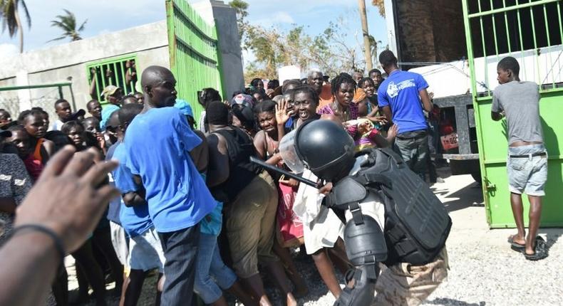 A Haitian policeman pushes back Hurricane Matthew victims waiting for the delivery of food from the UN's World Food Programme in Tobeck, in Les Cayes, in the south west of Haiti on October 13, 2016