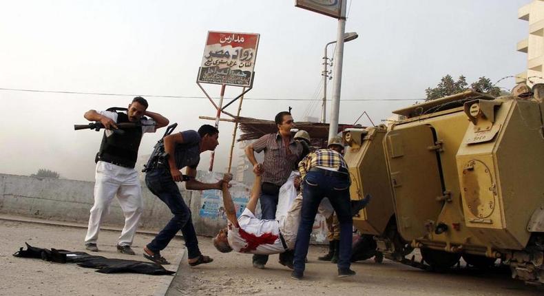 Egyptian security forces carry the lifeless body of Giza Police Gen. Nabil Farrag, center, who was killed after unidentified militants opened fire on security forces in the town of Kerdasa, Egypt.