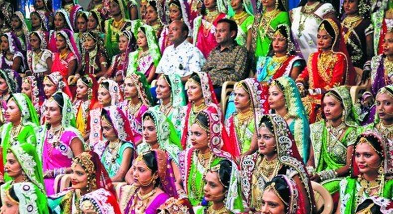 Indian diamond trader Mahesh Savani (top centre) wearing white, poses for a group photo along with brides before mass wedding hosted by him in Surat, India. 