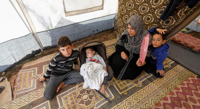 Displaced Palestinian woman sits with her children inside their tent where they take shelter, as the conflict between Israel and Hamas continues, at Nasser hospital in Khan Younis, in the southern Gaza Strip December 2, 2023.REUTERS/Saleh Salem