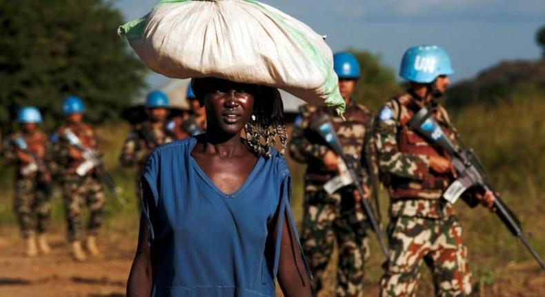 A displaced woman carries goods as UN peacekeepers patrol outside UN Protection of Civilians premises in Juba