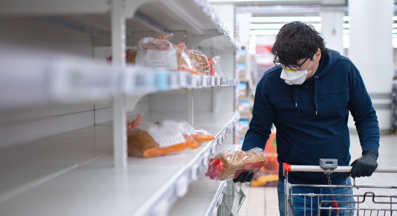 A grocery store shopper browses a limited supply of bread.
