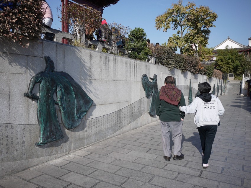 chinese couple walking pass chinese poetry wall