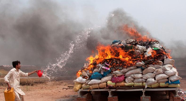 A member of Pakistan's Anti-Narcotics Force pours gasoline on a pile of confiscated drugs on the outskirts of Islamabad June 26, 2013.