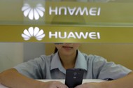 FILE PHOTO: A sales assistant looks at her mobile phone as she waits for customers behind a counter 