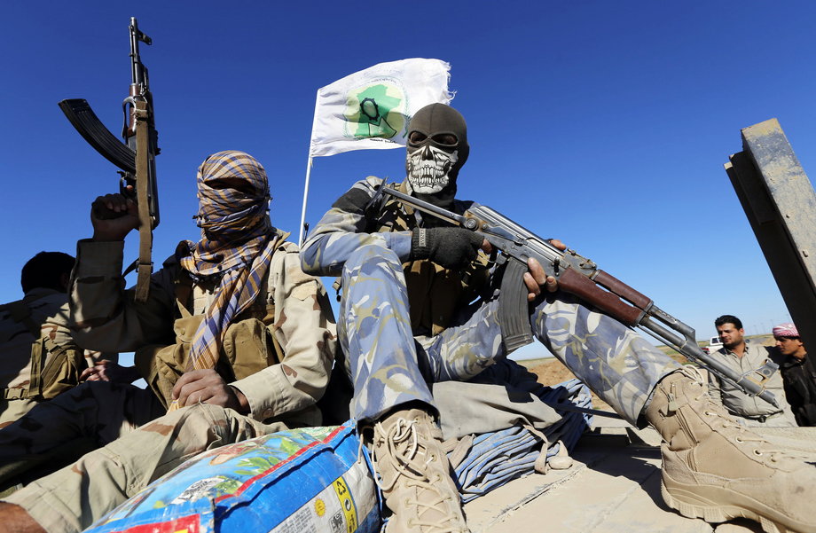 Masked Shi'ite fighters hold their weapons in Al Hadidiya, south of Tikrit, en route to the Islamic State-controlled al-Alam town, where they are preparing to launch an offensive on Saturday, March 6, 2015.
