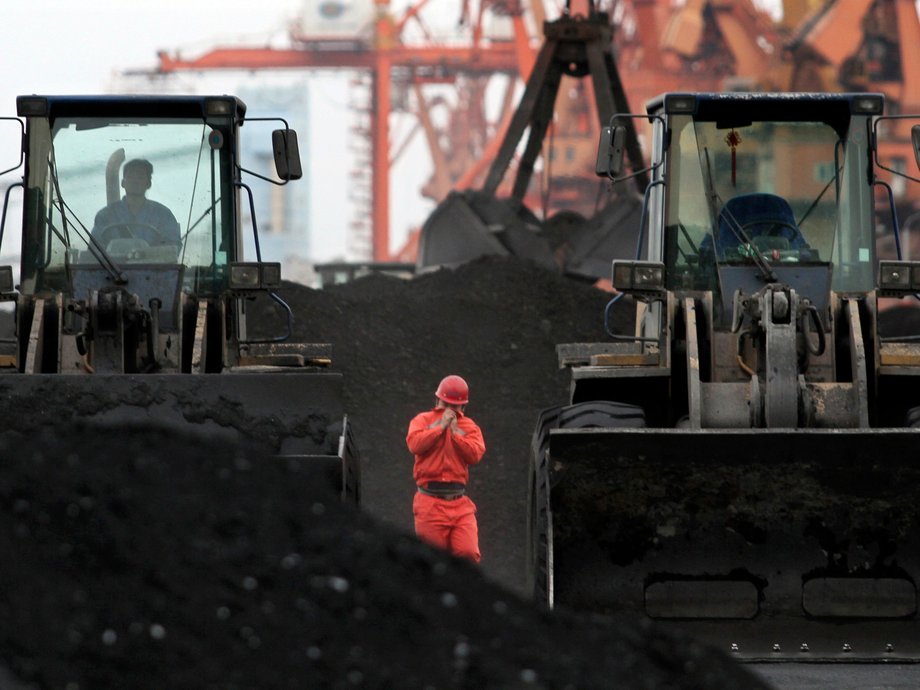 An employee walks between loaders used to move coal from North Korea at Dandong port, China, in 2010.