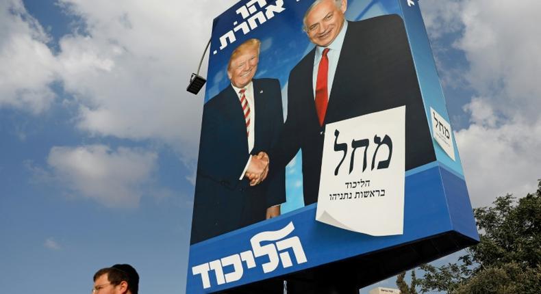 An Isreaeli man walks past an election billboard for the Likud party, showing US President Donald Trump (L) shaking hands with Prime Minister Benjamin Netanyahu in Jerusalem: Trump said Israel's latest election will be 50/50