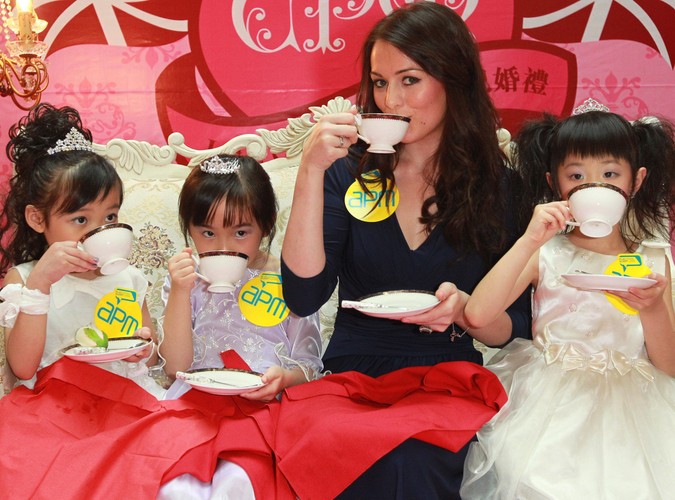 21-letnia Kate Bevan - sobowtór Kate Middleton - instruuje chińskie dziewczynki, jak grzecznie pić herbatę w centrum handlowym w Kwun Tong w Hong Kongu