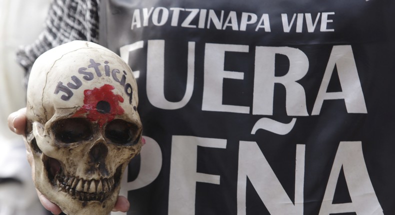 A woman holds a skull during a march marking 14-month anniversary of the disappearance of the students from the Ayotzinapa school, in Mexico City, November 26, 2015. The skull reads Justice and the shirt says Pena out, referring to Mexican President Enrique Peña Nieto.