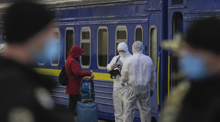 Védőruházatot viselő munkások ellenőrzik egy utas iratait a kijevi vasútállomáson 2020. március 27-én. / Fotó: MTI/EPA/Szerhij Dolzsenko