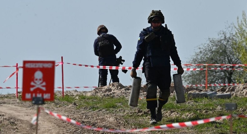 A Ukrainian deminer carries unexploded material during demining work at an airport in Hostomel, Ukraine.SERGEI SUPINSKY/AFP via Getty Images