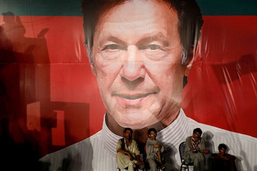 FILE PHOTO: Labourers, who set up the venue, sit under a wall with a billboard displaying a photo of