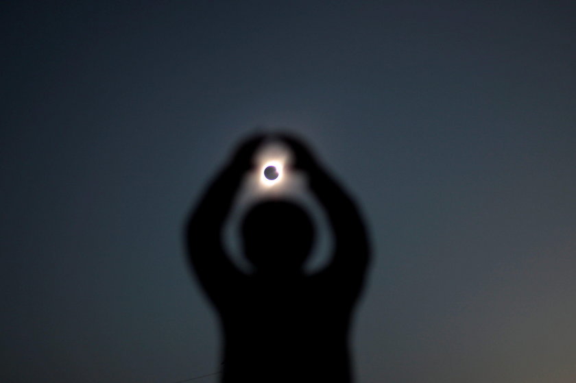 A mas wears a mask and a pair of eclipse glasses to observe a solar eclipse at La Serena