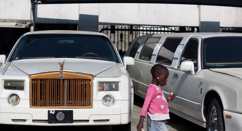 An African girl walks in front of luxury cars